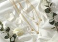 Brautschmuck Layering Flat-Lay mit drei Goldketten verschiedener Längen auf weißem Satin