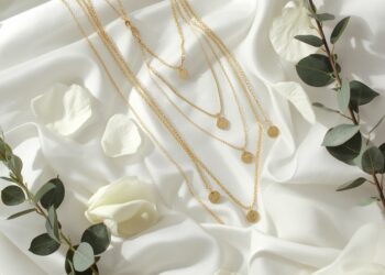 Brautschmuck Layering Flat-Lay mit drei Goldketten verschiedener Längen auf weißem Satin