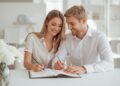 Mann und Frau schreiben gemeinsam in ein Journal und planen ihre Lebensziele