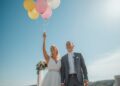 Brautpaar lässt gemeinsam bunte Luftballons mit Wünschen in den sonnigen Himmel steigen