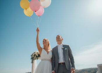 Brautpaar lässt gemeinsam bunte Luftballons mit Wünschen in den sonnigen Himmel steigen