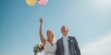 Brautpaar lässt gemeinsam bunte Luftballons mit Wünschen in den sonnigen Himmel steigen