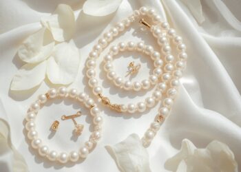 Klassischer Brautperlenschmuck – Perlenkette, Ohrstecker und Armband auf weißem Satin